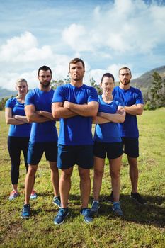 Group of fit people together with arms crossed in a boot camp on a sunny day