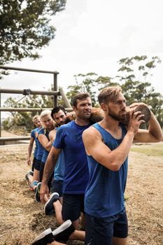 Fit people holding a heavy wooden log during boot camp training