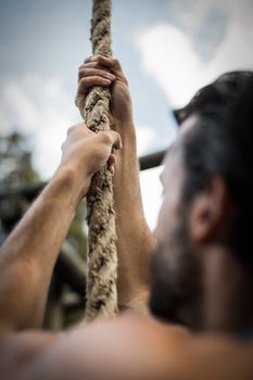 Man climbing a rope during obstacle course in boot camp