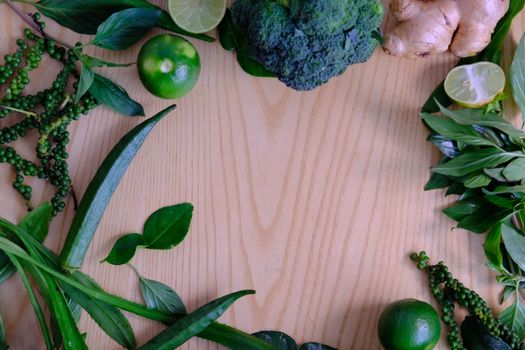 Background with assorted green vegetables of ripe fresh broccoli, ginger, lime, avocado, green pepper, Green okra and basil leaves on wooden background. 