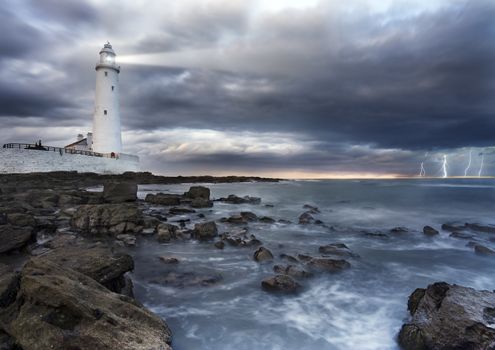 A view of a lighthouse, looking out to sea, with lightning bolts on the horizon.