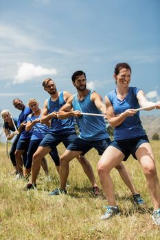 People playing tug of war during obstacle training course in boot camp