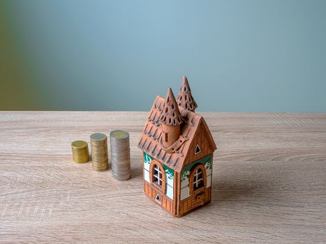 Model of a house and Stack of European Euro coins On Wooden Table. Selective Focus. Real estate agency, mortgage loan, lottery, buying property.Home loan and investment concept. Copy space