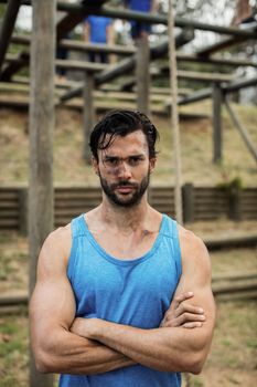 Portrait of determined man standing with arms crossed in boot camp training during day