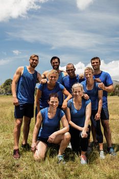 Group of fit people posing together in boot camp on a sunny day