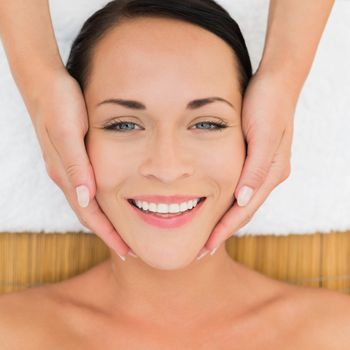 Peaceful brunette enjoying a facial massage in the health spa