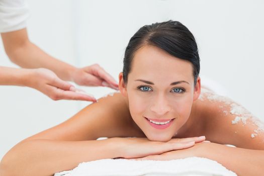 Peaceful brunette getting a salt scrub beauty treatment in the health spa