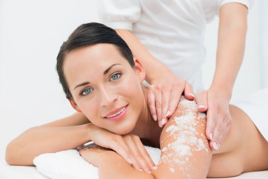 Peaceful brunette getting a salt scrub beauty treatment in the health spa