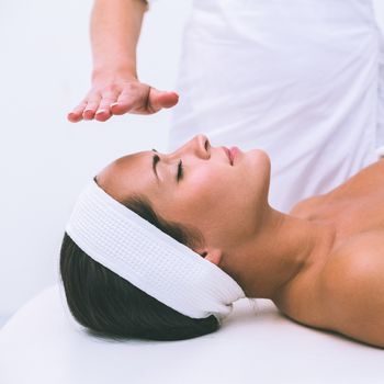 Peaceful brunette getting reiki therapy in the health spa