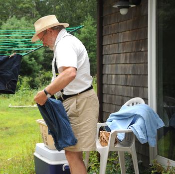 Country gentleman washing and line drying clothes outside.