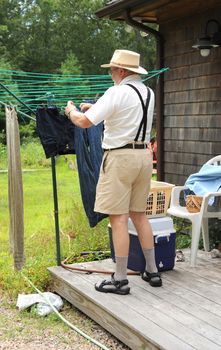 Country gentleman washing and line drying clothes outside.