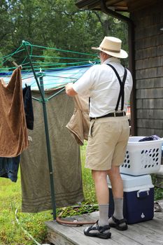 Country gentleman washing and line drying clothes outside.