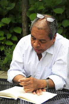 African american male writing on a table outdoors.