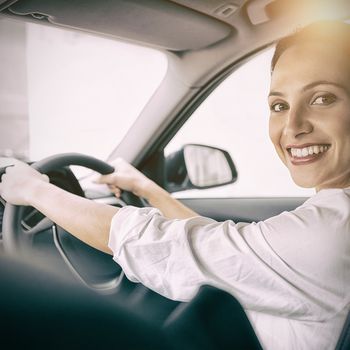 Woman holding steering wheel and smiling at camera 