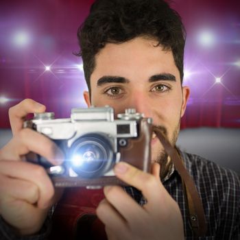 Casual man taking a photo against curtains of red color 