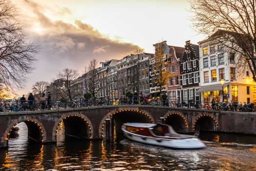 Amstedam, capital of Netherlands. Beautiful tranquil scene of city of Amsterdam at dusk. Bicycles along the street and on the bridge over the canal.