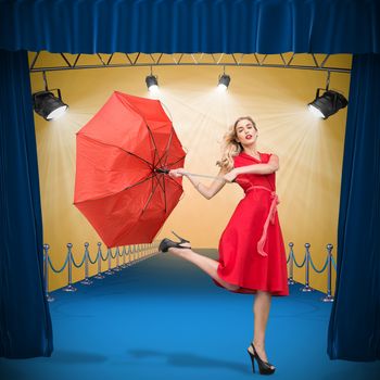Elegant blonde holding umbrella against curtains of red color 