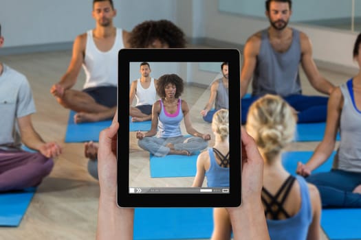 Close-up of hands holding digital tablet against instructor taking yoga class