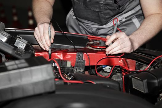 Male hands performing car repair with open hood