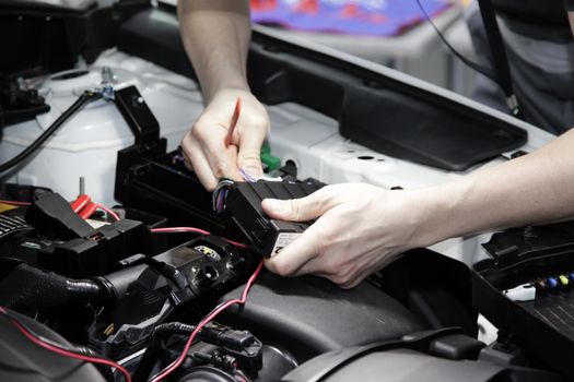 Male hands performing car repair with open hood