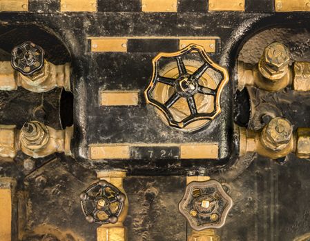 Golden and black control valves of an old steam engine in Asukayama Park in the Kita District of Tokyo, Japan.