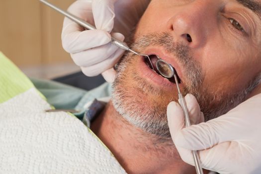 Dentist examining a patients teeth in the dentists chair at the dental clinic