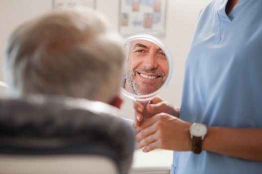 Dentist showing patient his new smile in the mirror at the dental clinic