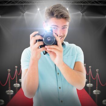 Handsome young man holding digital camera against white background with vignette