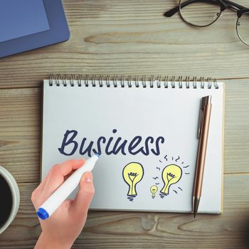 Businesswomans hand writing with marker against overhead view of coffee with office supplies