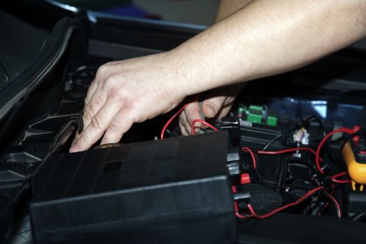 Male hands performing car repair with open hood