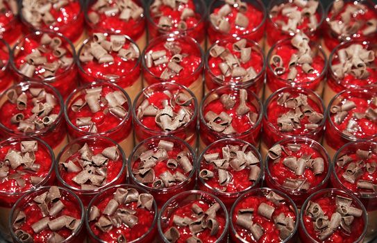 Mini desserts of red mousse in small glasses sprinkled with chocolate