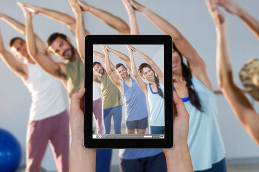 Close-up of hands holding digital tablet against instructor taking yoga class