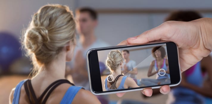 Hand holding mobile phone against white background against instructor taking yoga class