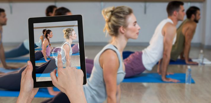 Hands touching digital tablet against white background against side view of people performing yoga