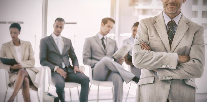 Serious businessman standing in  front of business people in office