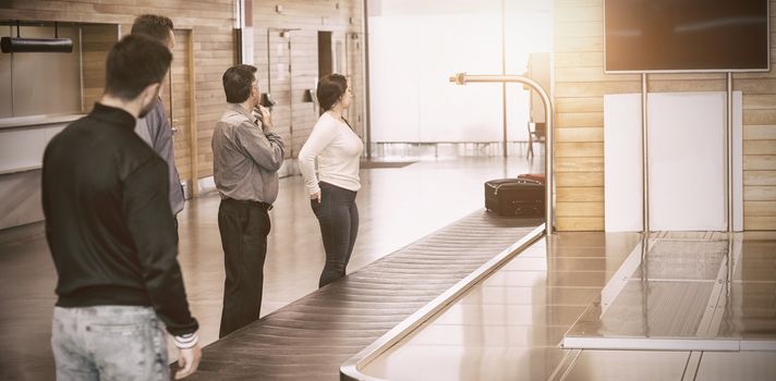 People waiting by baggage claim for luggage at airport