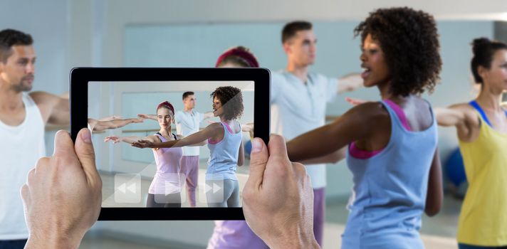 Cropped hand holding digital tablet against yoga instructor helping student with correct pose