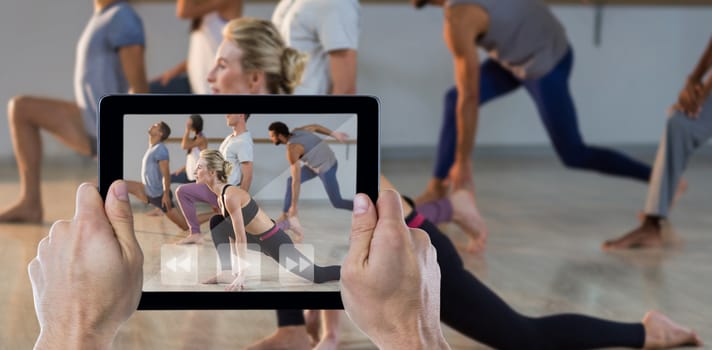 Cropped hand holding digital tablet against people performing stretching exercise