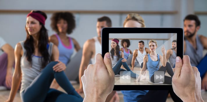 Cropped hand holding digital tablet against group of people performing yoga