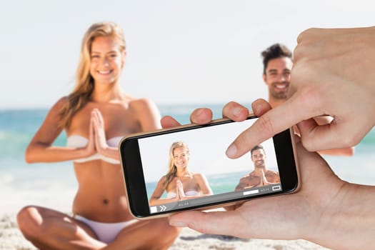 Hands touching smart phone against happy couple doing yoga 