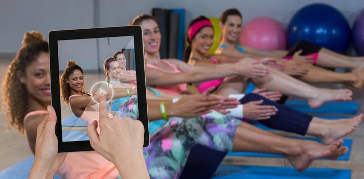 Hands touching digital tablet against white background against portrait of women performing yoga