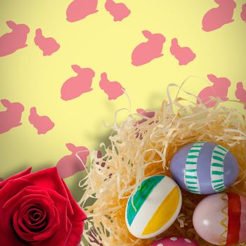 Picture of a rose against multi colored easter eggs on paper nest