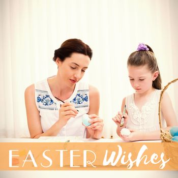 Mother and daughter painting easter eggs against easter greeting