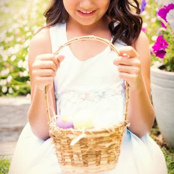 Happy girl collecting easter eggs in the garden