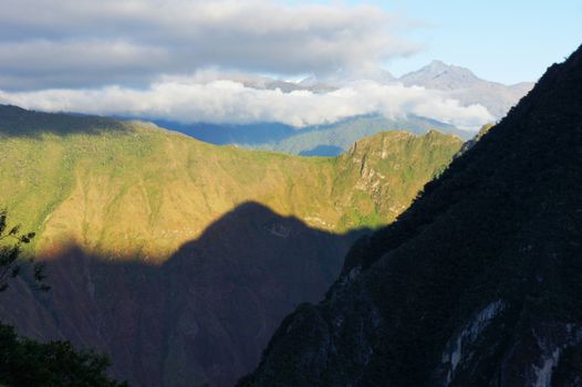 The sun breaks over the mountains and shines its first light on Machu Picchu mountain