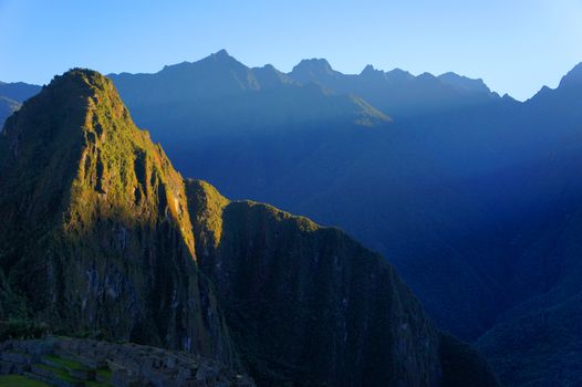 The sun breaks over the mountains and shines its first light on Machu Picchu mountain