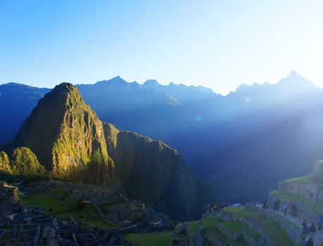 The sun breaks over the mountains and shines its first light on Machu Picchu mountain