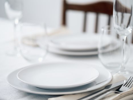 Beautiful table setting in white colors. Empty white plates. Set table for romantic dinner for two at home