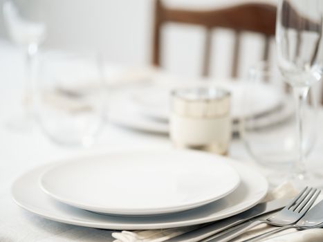 Beautiful table setting in white colors. Empty white plates. Set table for romantic dinner for two at home