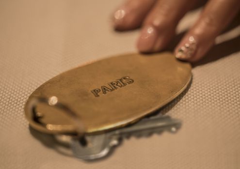 Hand of woman with key of luxury hotel room in France in Paris